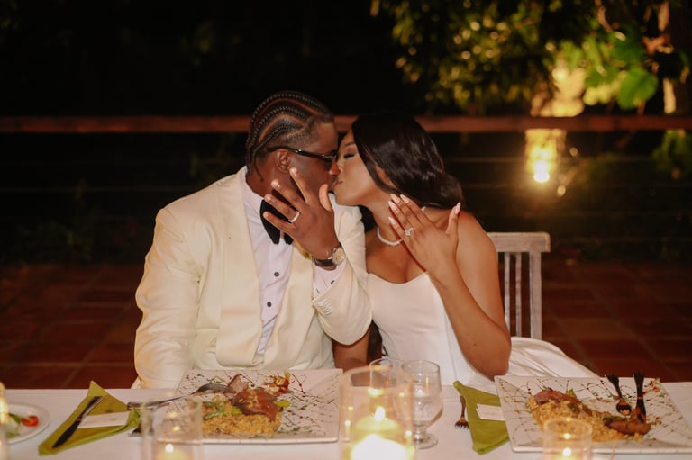 Couple sharing an intimate moment at an elegant outdoor dinner table with candles and place settings at night