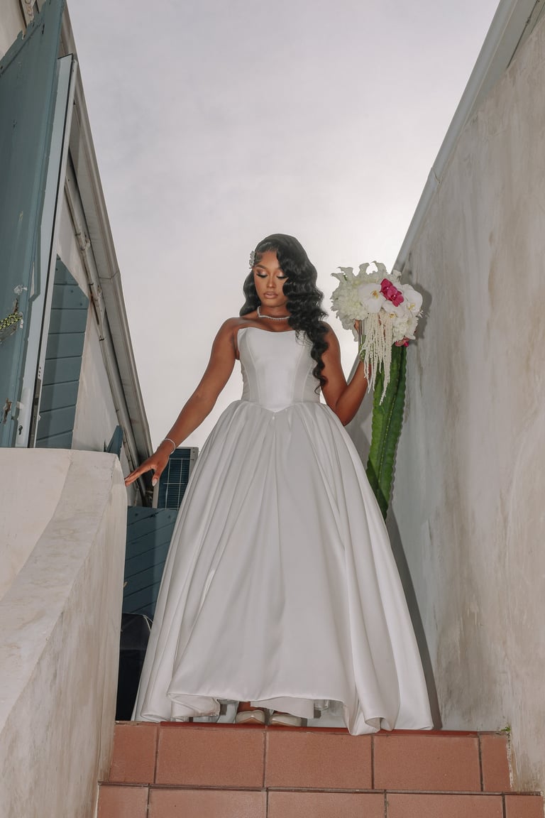 Woman in white wedding dress holding cascading floral bouquet standing in modern architectural passageway