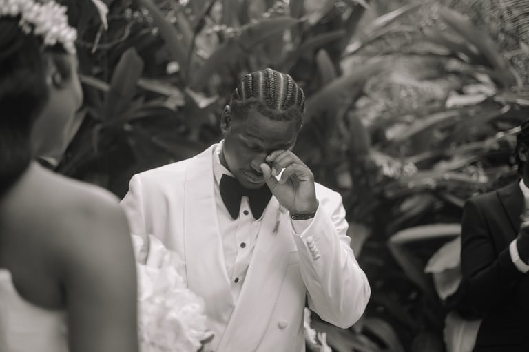 Man in white tuxedo wiping his face with hand at formal event, black and white photograph