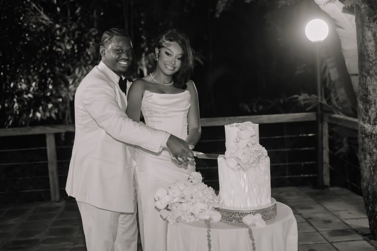 Newlyweds cutting their wedding cake at night outdoors, black and white photo