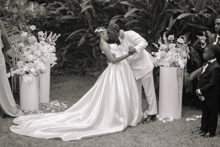 Bride and groom dancing under a floral arch at outdoor wedding ceremony in black and white